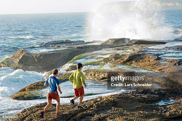 runners on rocky pacific coast. - headland stock pictures, royalty-free photos & images