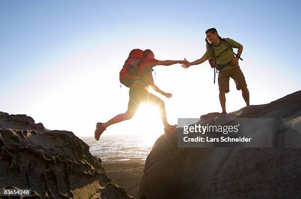 hikers jump on rocky pacific coast. - jumping australia stock-fotos und bilder
