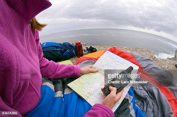 reading map & gps at camp on rocky ocean cliff. - one person missing stock pictures, royalty-free photos & images
