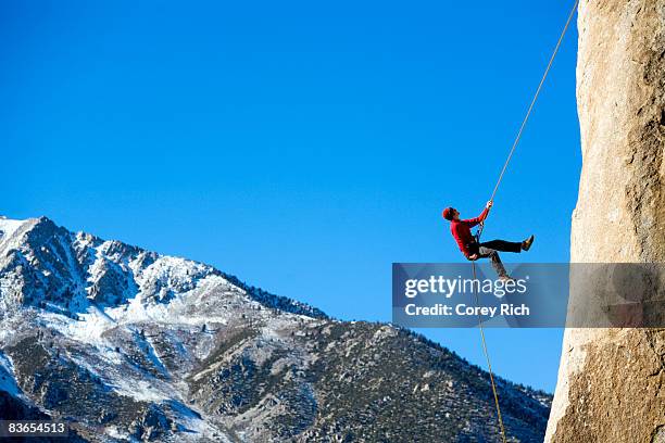 climber rappelling down boulder - abseilen stockfoto's en -beelden