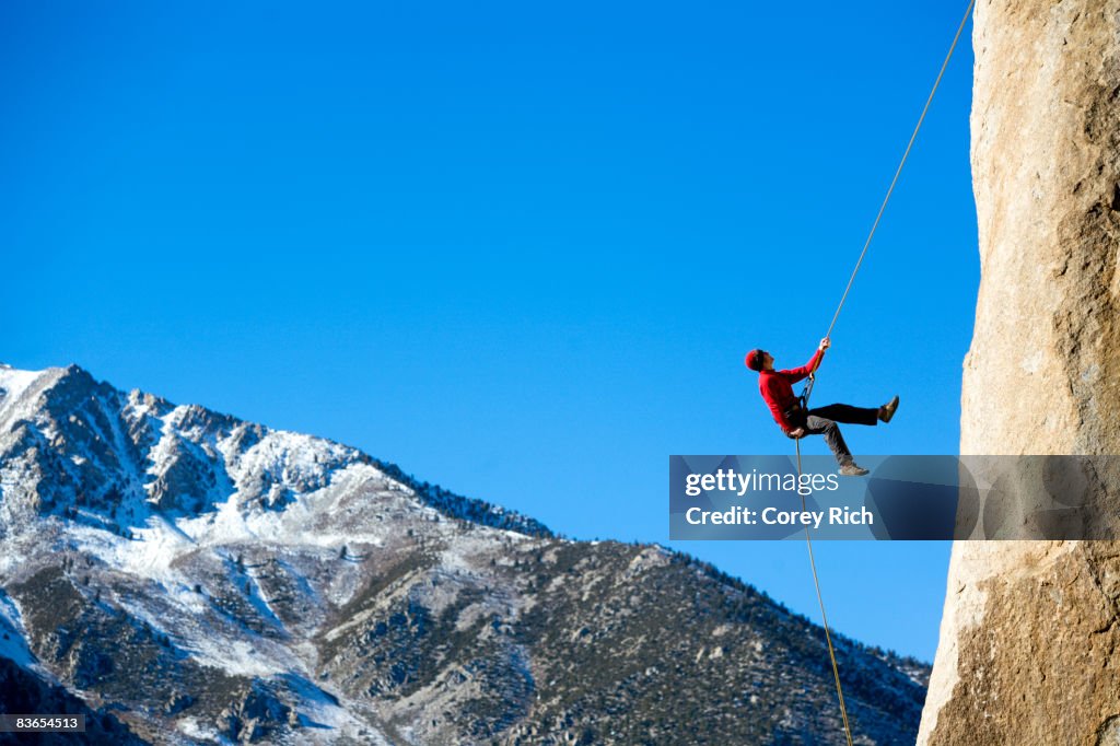 Climber rappelling down boulder