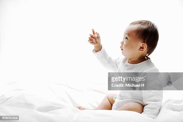 baby who sits on sheet - bed on white stock pictures, royalty-free photos & images