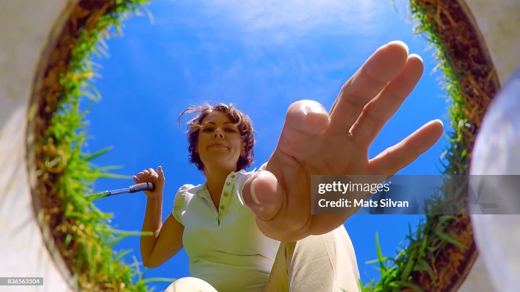 Woman Picking Up her Golf Ball From the Hole