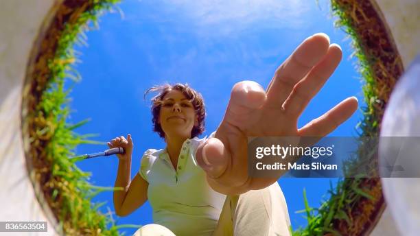 woman picking up her golf ball from the hole - low angle view stock-fotos und bilder