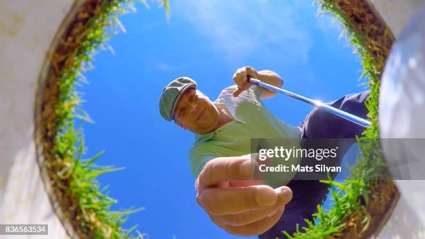 man with flat cap picking up his golf ball from the hole - clothing shot flat stock pictures, royalty-free photos & images