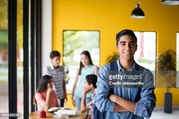 male college student standing with students in background - latin american and hispanic ethnicity student stock pictures, royalty-free photos & images