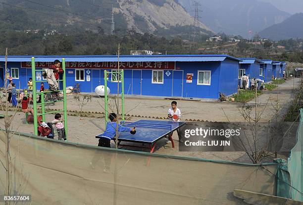 Children play the table tennis at a tent camp in Leigu township of Beichuan county, in China's southwestern province of Sichuan on November 10, 2008....