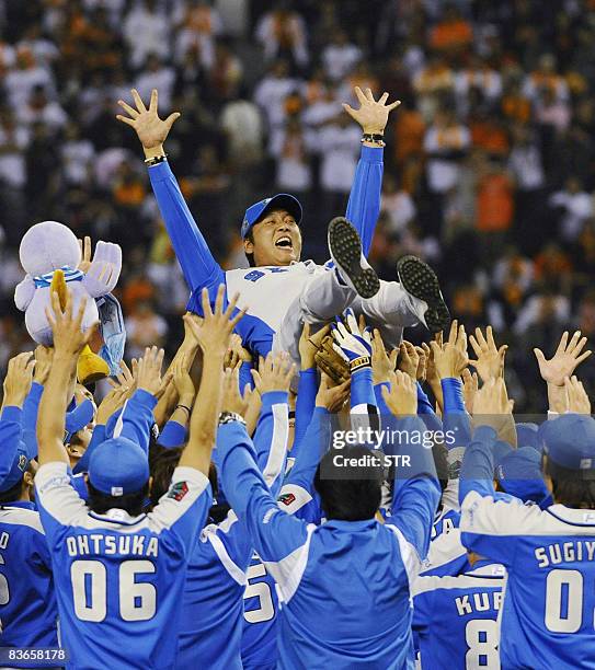 Japan's professional baseball Pacific League champion team Seibu Lions members toss up their manager Hisanobu Watanabe in the air as they defeated...
