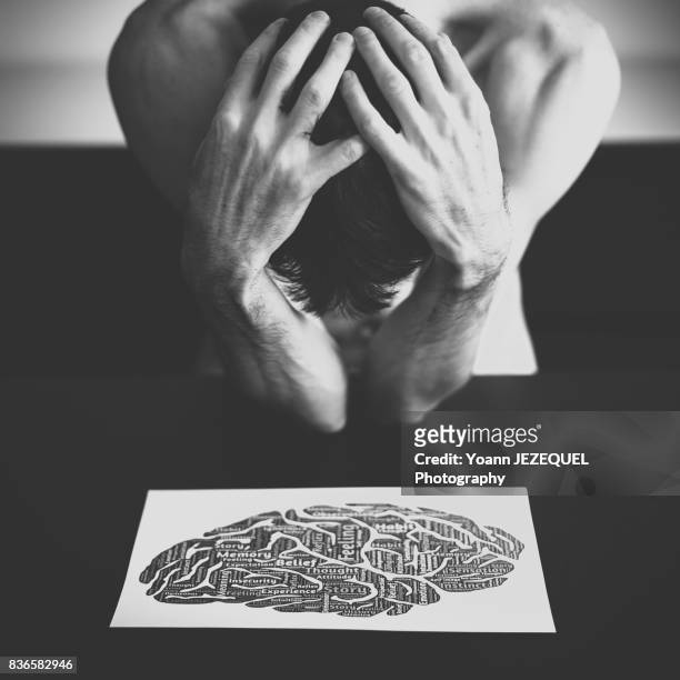 young man depressed patient takes his head in his hands - hate stock-fotos und bilder
