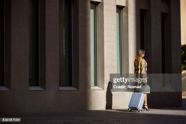 rear view of businesswoman walking by airport - trench coat stock pictures, royalty-free photos & images