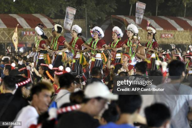 This picture taken on August 19, 2017 shows members of the Amis indigenous group joined by men and tourists in a dance during the traditional harvest...