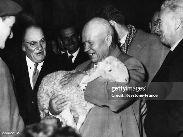 Nikita Khrouchtchev reçoit l'offrande traditionnelle d'un agneau vivant qu'il tient dans ses bras lors de sa visite à Pau, France le 27 mars 1960.