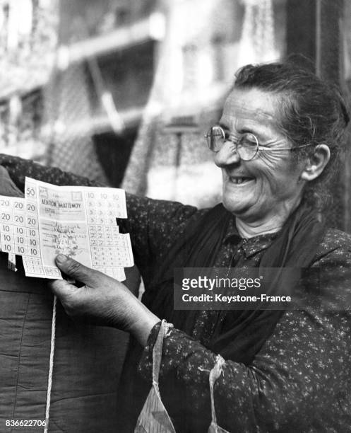 Une femme grecque montre avec joie ses tickets de rationnement pour des vêtements et de la literie, circa 1940 en Grèce.