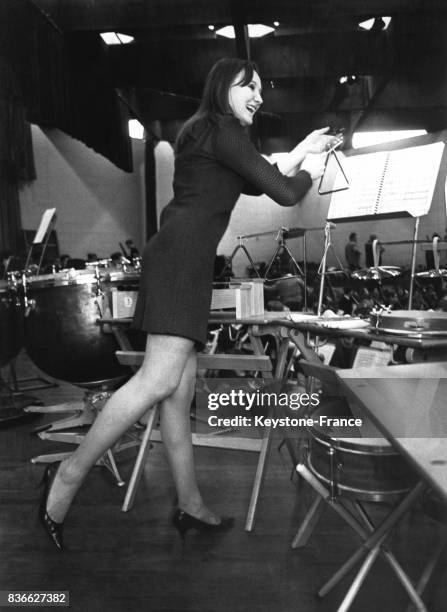 Leslie Cooper, étudiante de 18 ans, joue du triangle lors d'une répétition musicale pour un festival de musique scolaire le 2 janvier 1968 à Londres,...