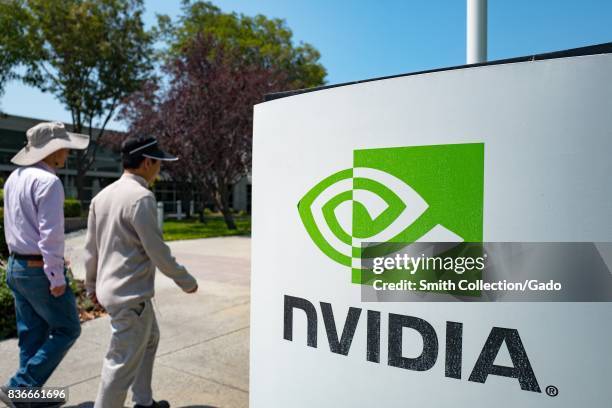 Two men walk together past signage with logo at the Silicon Valley headquarters of computer graphics hardware company Nvidia, Santa Clara,...