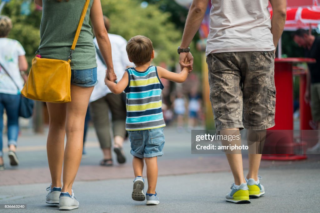 Rear view family walking together on summer day in amusement park