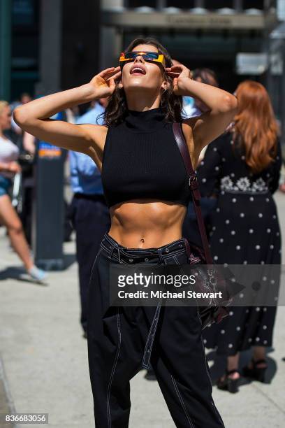 Model Georgia Fowler views the solar eclipse using solar glasses in Midtown on August 21, 2017 in New York, New York.