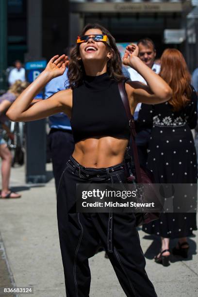 Model Georgia Fowler views the solar eclipse using solar glasses in Midtown on August 21, 2017 in New York, New York.