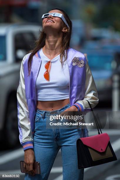 Model Barbara Fialho views the solar eclipse using solar glasses in Midtown on August 21, 2017 in New York, New York.