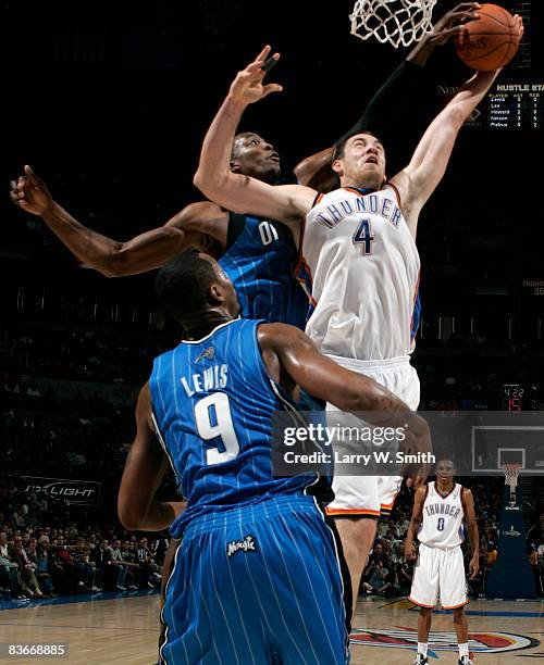 Nick Collison of the Oklahoma City Thunder attempts a layup while being guarded by Rashard Lewis and Dwight Howard of the Orlando Magic at the Ford...