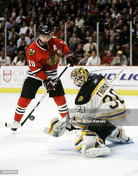 Goaltender Tim Thomas of the Boston Bruins makes a save as Patrick Sharp of the Chicago Blackhawks closes in during the second period at the United...