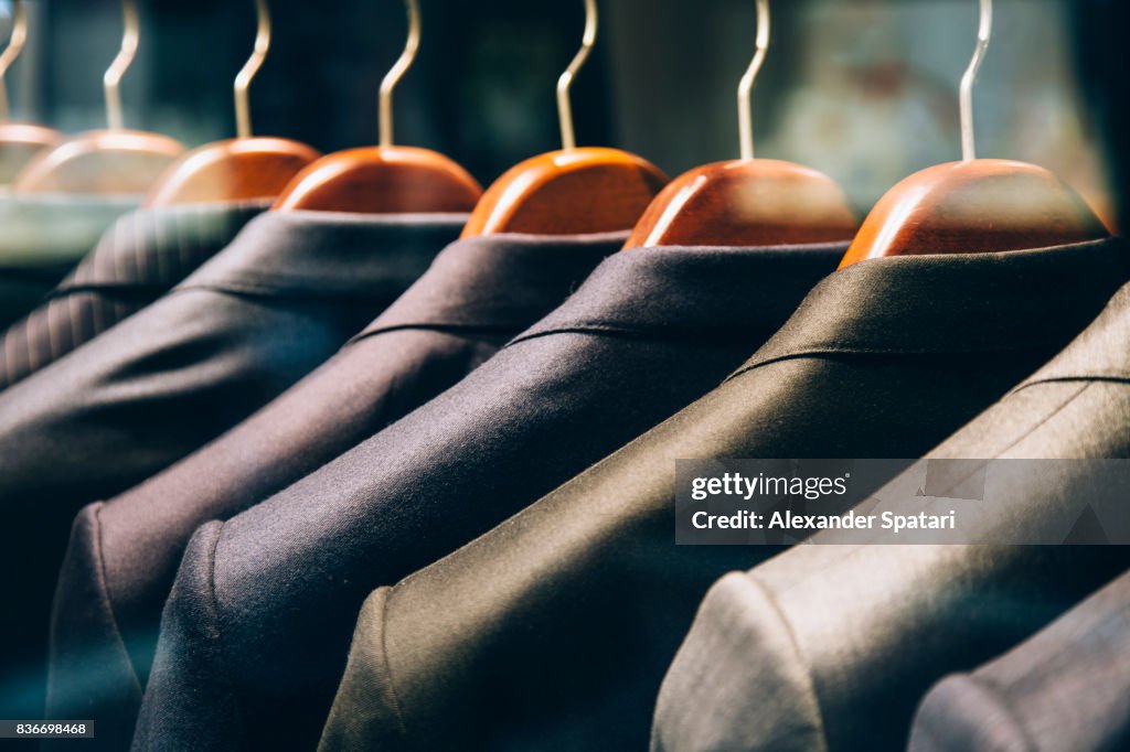 Men's suits hanging in a row on clothing rack