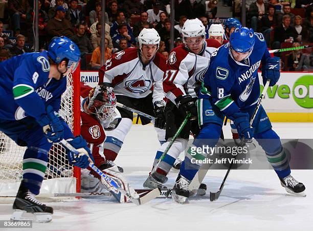 Steve Bernier of the Vancouver Canucks and teammate Taylor Pyatt try to push the puck past Peter Budaj of the Colorado Avalanche with teammates Scott...