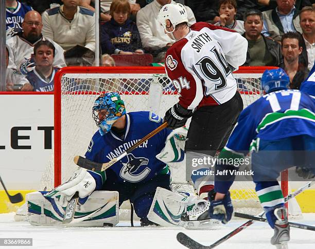 Roberto Luongo of the Vancouver Canucks makes a save with Ryan Smyth of the Colorado Avalanche near his crease during their game at General Motors...