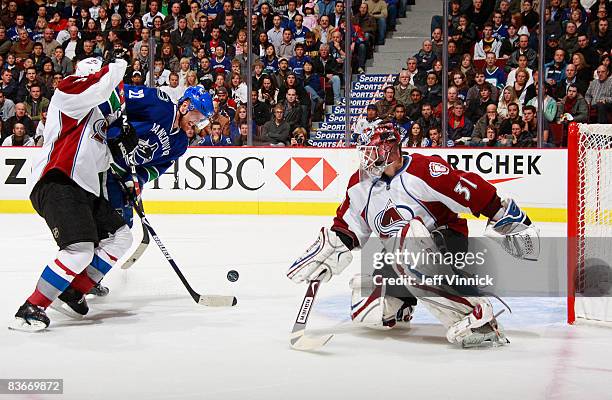 Daniel Sedin of the Vancouver Canucks tries to get a shot off in close on Peter Budaj of the Colorado Avalanche during their game at General Motors...