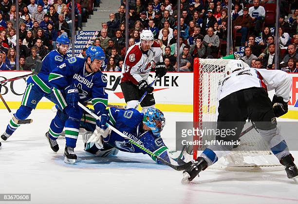Roberto Luongo of the Vancouver Canucks dives to make a save on Paul Stastny of the Colorado Avalanche while teammates Willie Mitchell and Ryan...