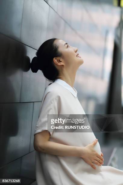 pregnant woman holding her belly with hands looking up - man and woman holding hands profile stock-fotos und bilder