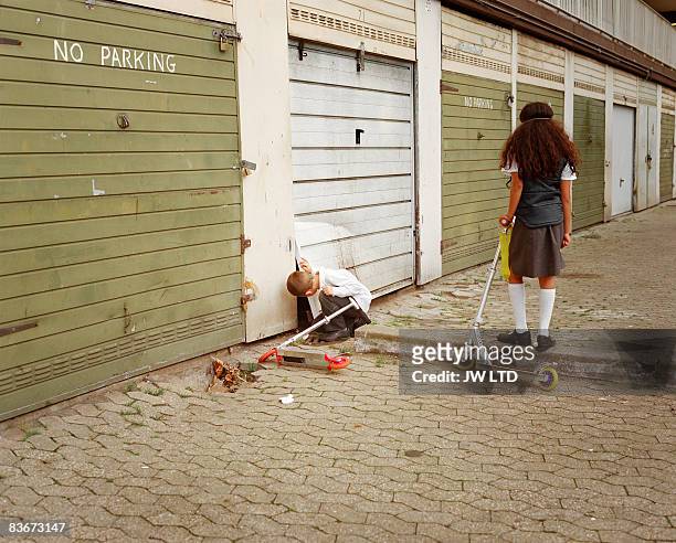 boy and girl playing by garage doors on housing estate  - elephant and castle ストックフォトと画像