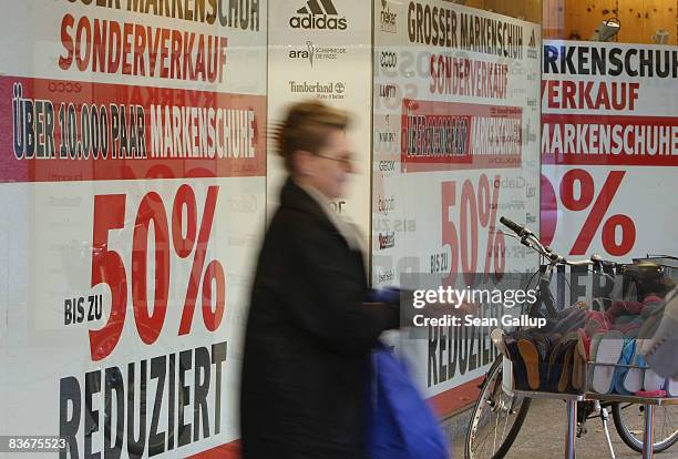 Woman walks past a storewindow advertisement showing drastic price reductions on November 13, 2008 in Berlin, Germany. The Organization for Economic...