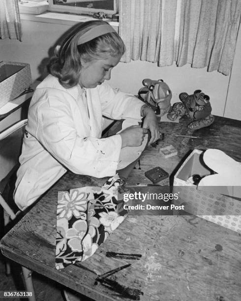 Darlene is sewing a cloth frog to be stuffed with bird seed for a toy. She is working in the Pride Workshop, 2265 S. Albiion, in an apartment court...