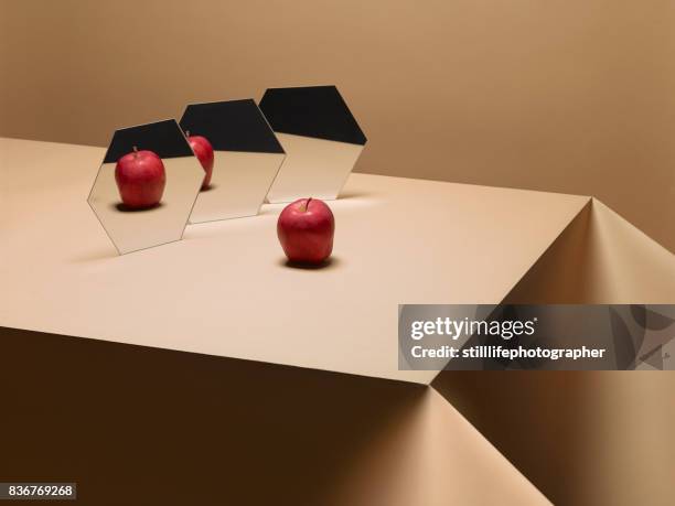one apple on table with mirrors - cloning stock-fotos und bilder