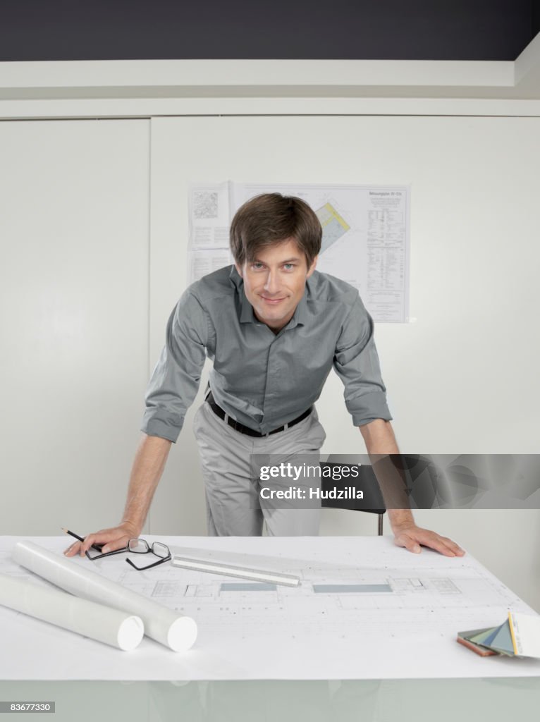 An architect leaning over blueprints on a desk