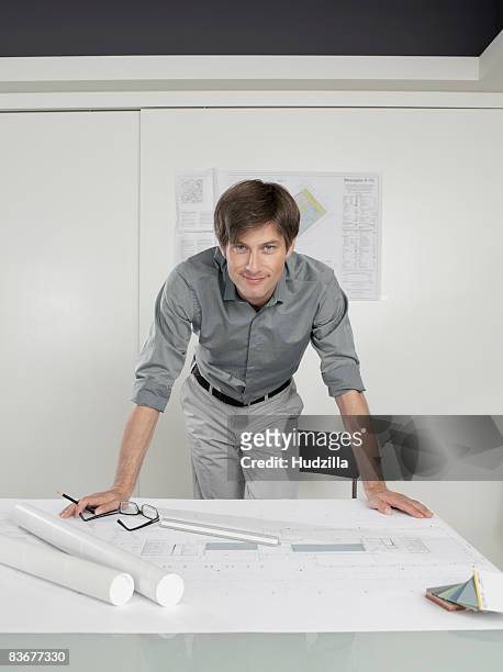 an architect leaning over blueprints on a desk - leaning stock pictures, royalty-free photos & images