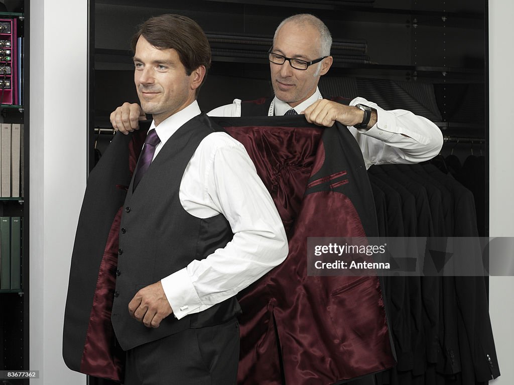 A tailor assisting a man trying on a suit