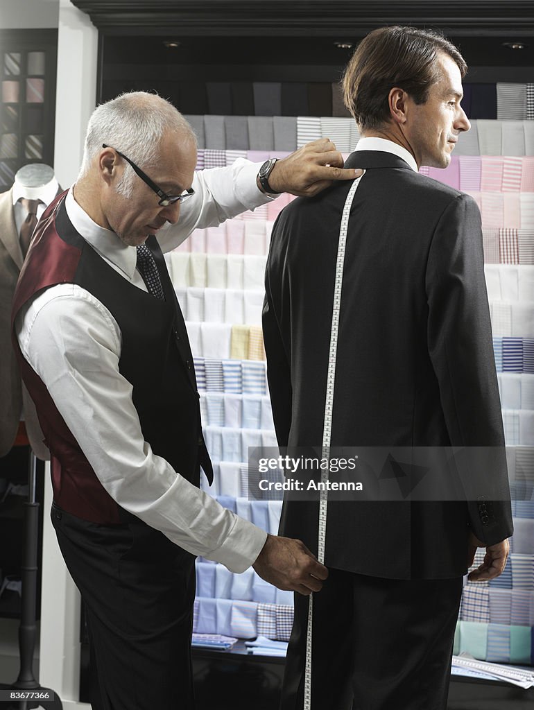 A tailor fitting a man with a suit