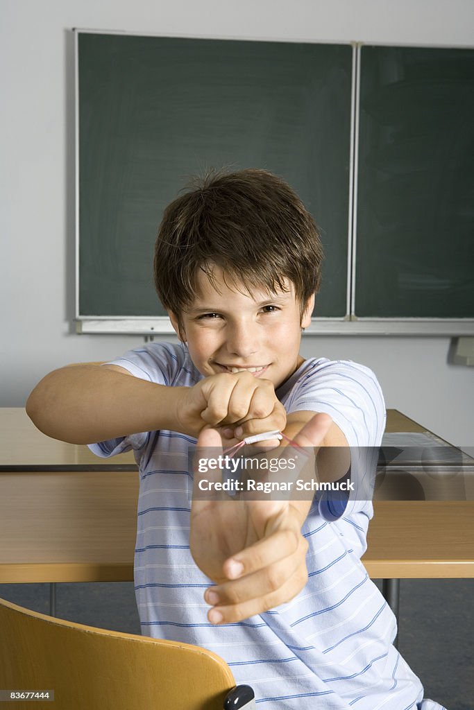 A pre-adolescent boy aiming a rubber band slingshot