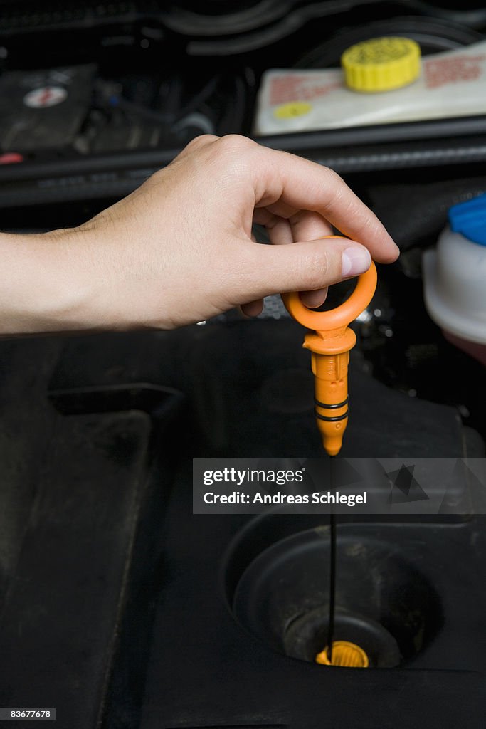 A person checking the oil in a car engine