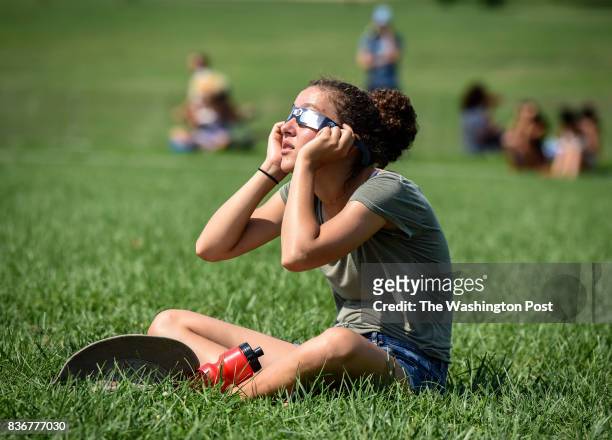 Karinne Weinberg, visiting from Montreal, observes a rare solar eclipse from her grassy perch on the National Mall, on August 2017 in Washington, DC.