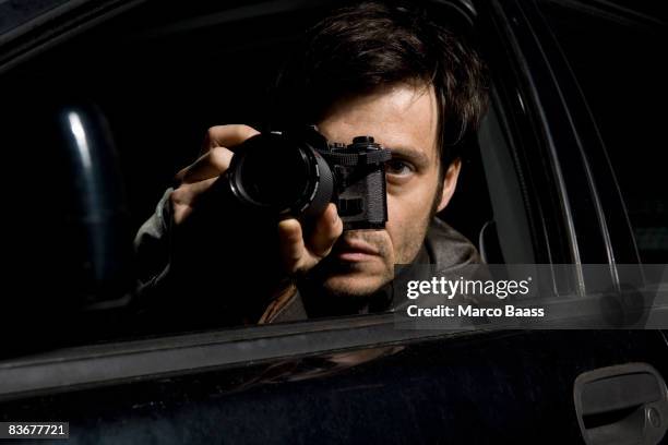 a man doing surveillance with a camera from his car - investigatore foto e immagini stock