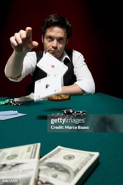 a man throwing two ace cards at a high stakes poker game - poker card game stockfoto's en -beelden