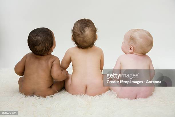 three babies sitting in a row, rear view - cute bums stockfoto's en -beelden