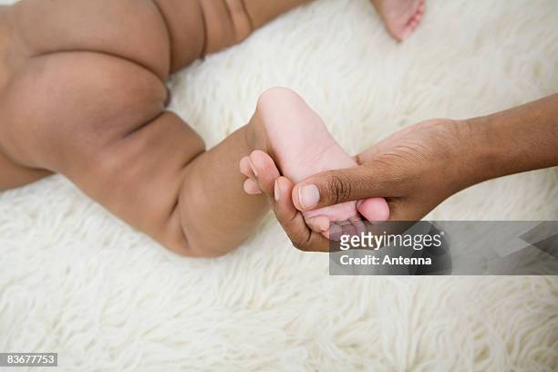 a human hand holding a baby's foot - boys bare bum 個照片及圖片檔