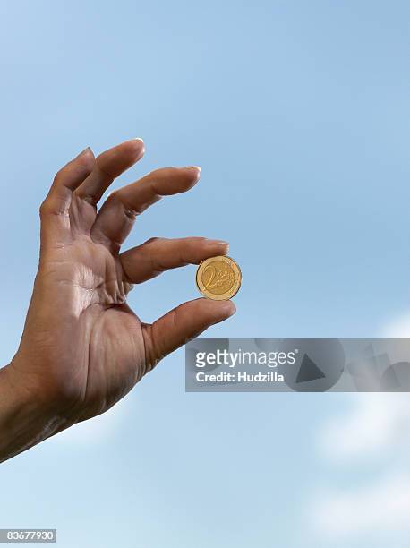 a human hand holding a two euro coin - zwei euro münze stock-fotos und bilder