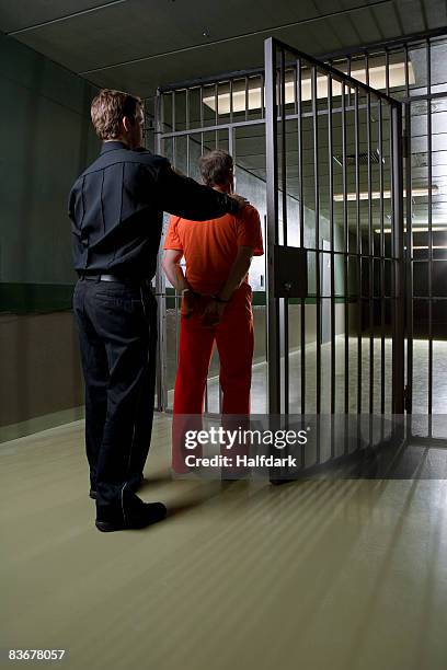 a prison guard leading a prisoner along a corridor - open prison cell stock pictures, royalty-free photos & images