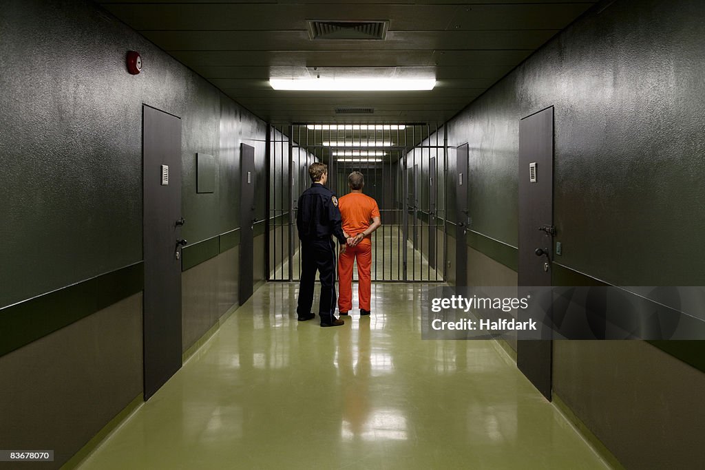 A prison guard leading a prisoner along a corridor