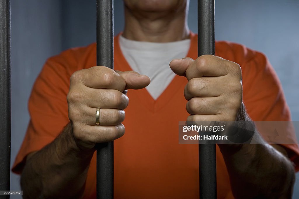 A prisoner standing behind prison bars